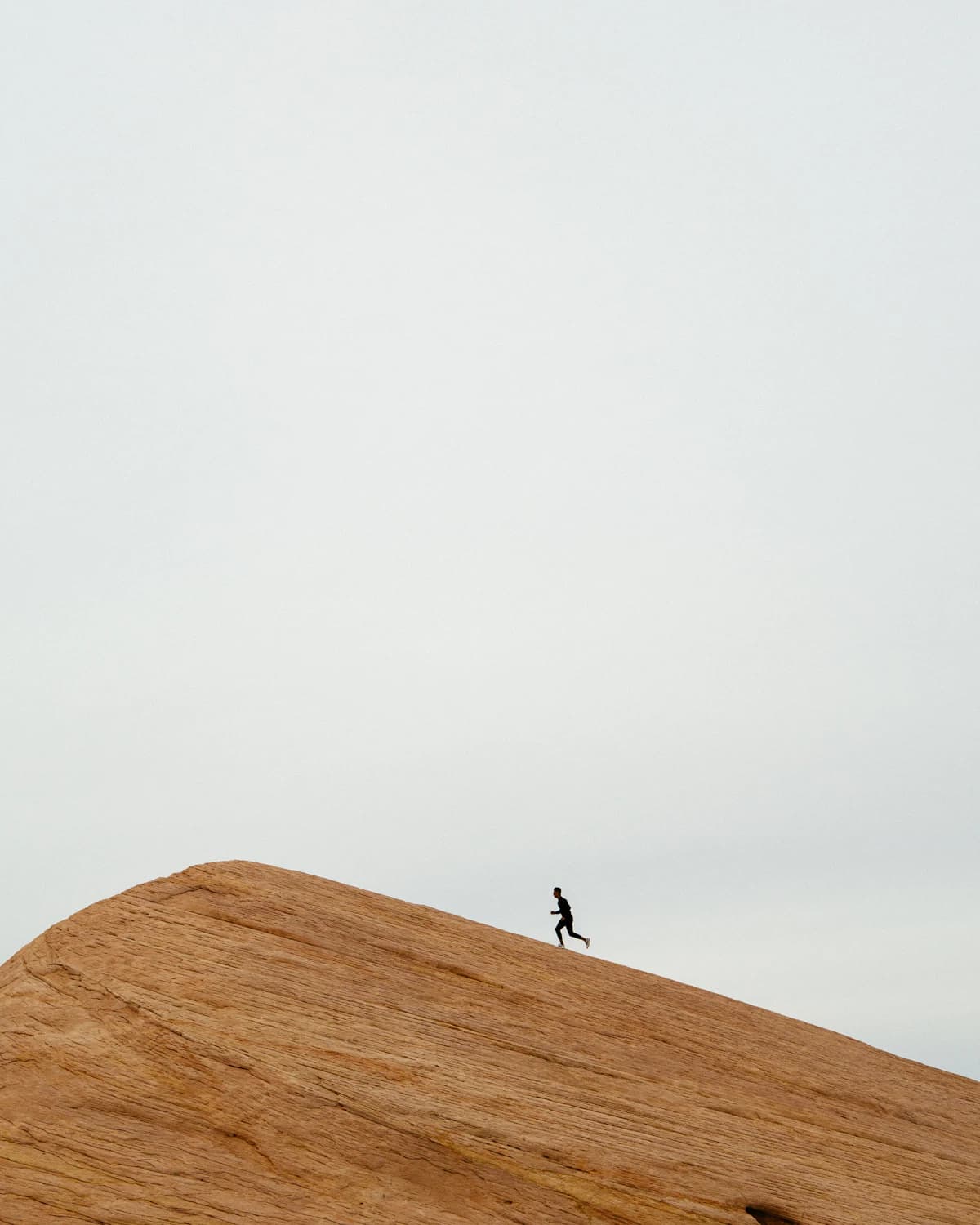 A runner cresting a rock dune